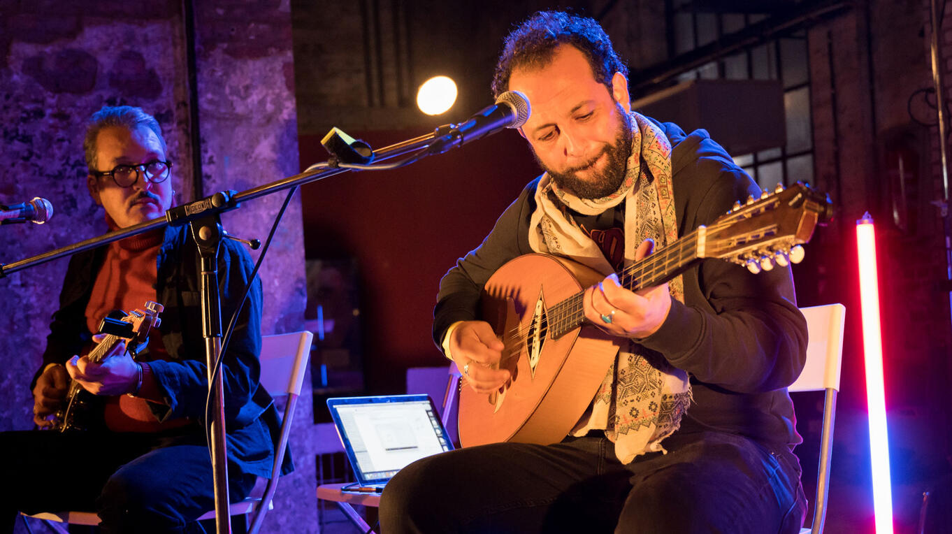 Kader Denednia playing mondol and singing, accompanied by a guitarist, during the Café Noailles concert at the Idle Films Hamburg premiere.
