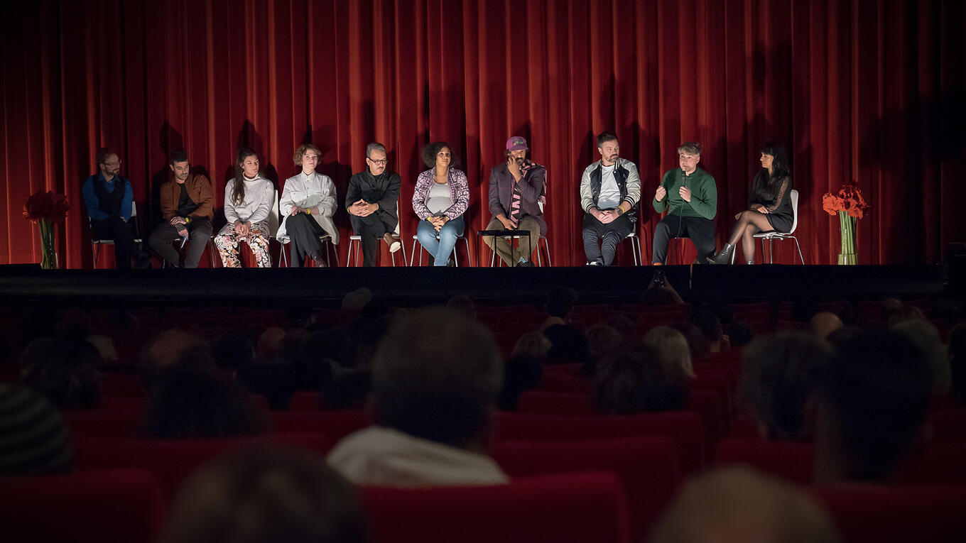 Audience Q&A at Idle Films premiere in Hamburg, with director Iliès Terki and cast on stage in front of a red curtain.