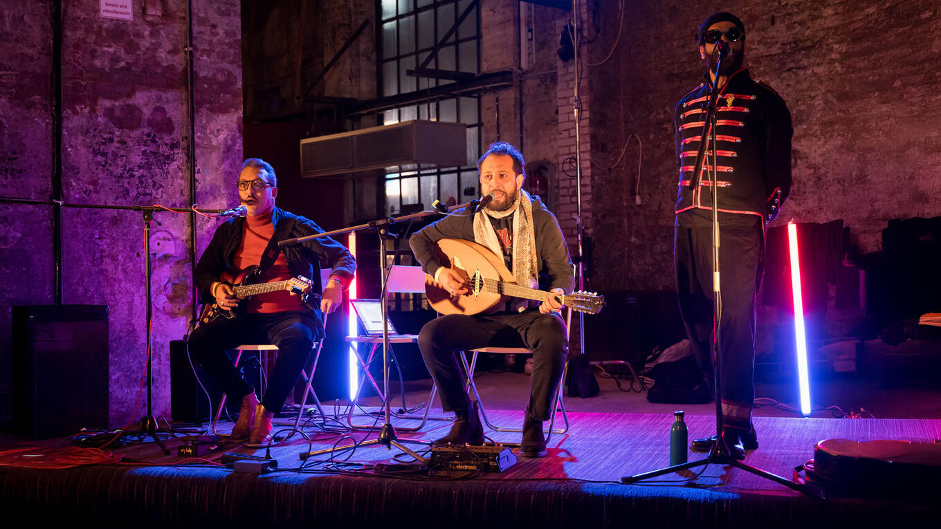 Café Noailles band members playing guitar and oud during an afterparty concert in an industrial hall near Zeise Kino.